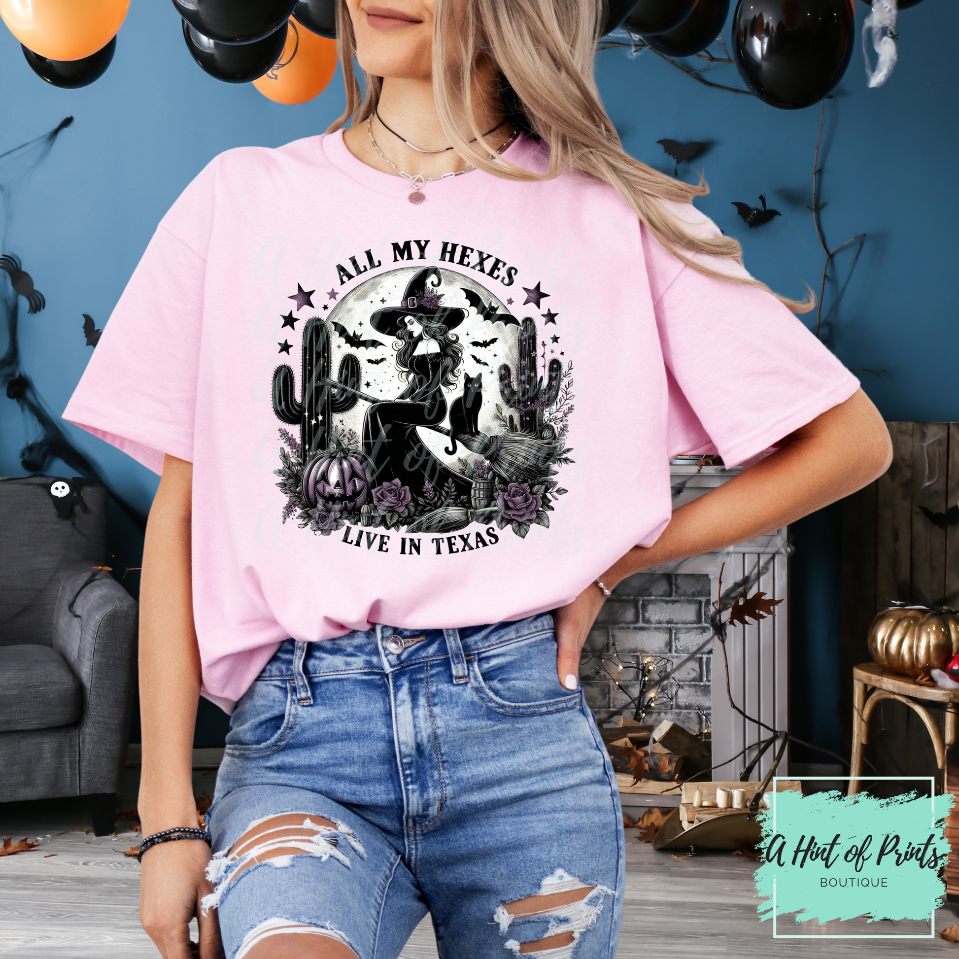 Person wearing a pink t-shirt with a graphic design and text, standing in a decorated room.