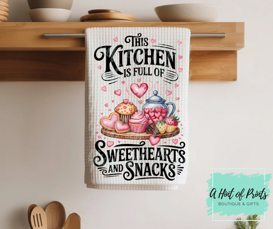 Decorative kitchen towel with sweet-themed design hanging on a wooden rack.